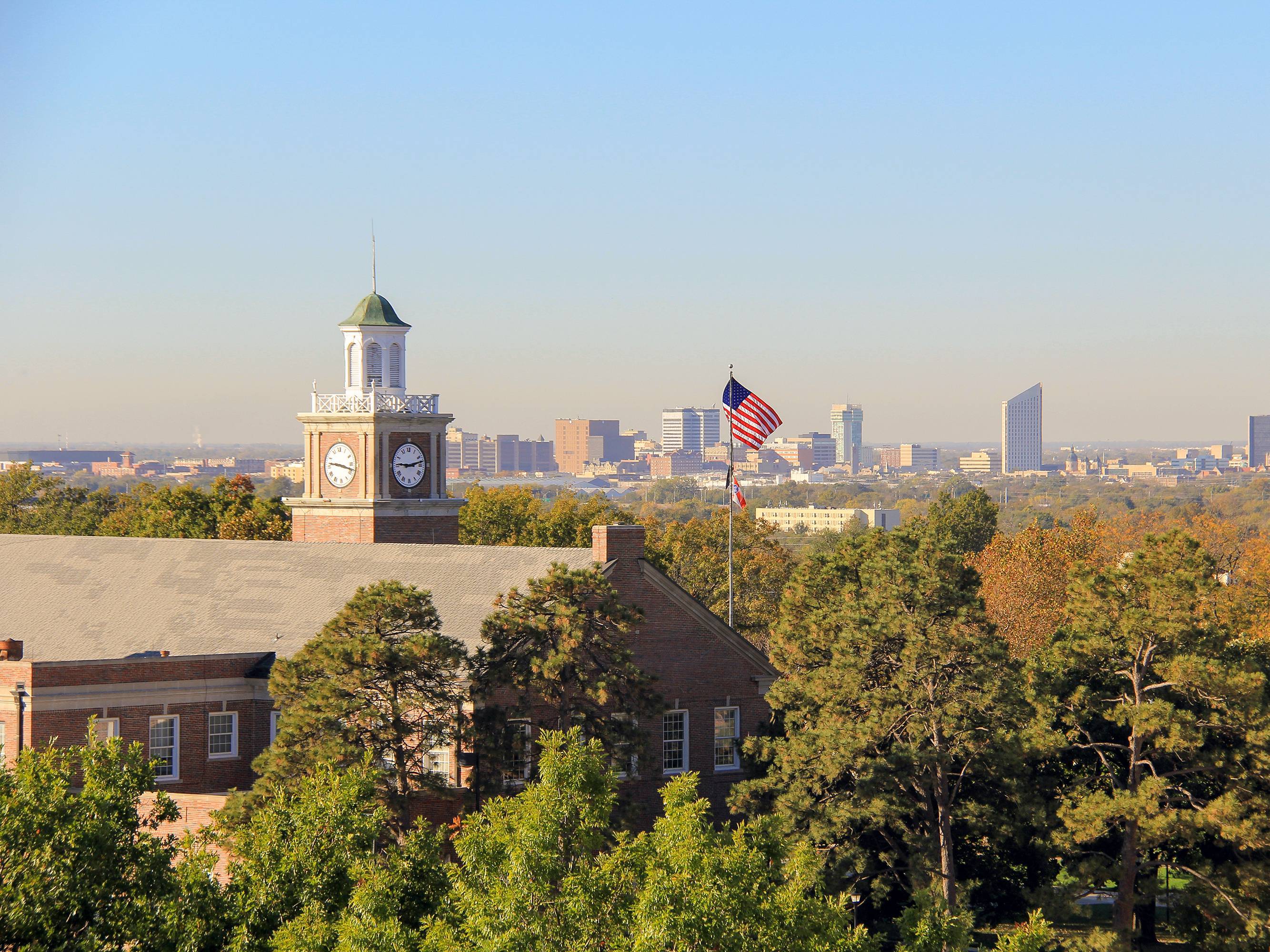 Downtown ͷ skyline visible behind the clock tower of Morrison Hall.